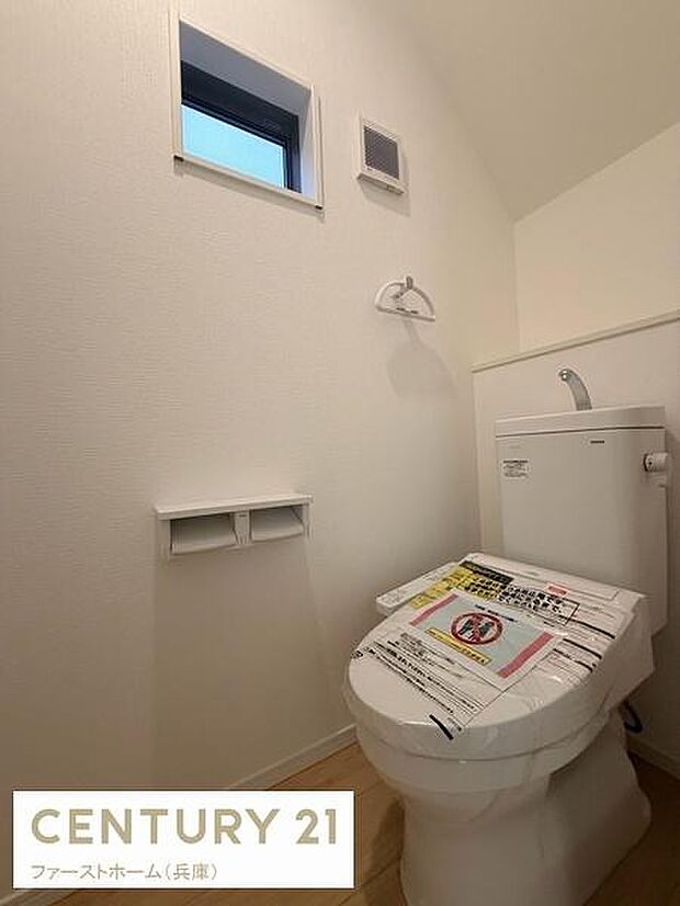 清潔感のある明るいトイレ空間です。窓があり換気しやすい設計となっています。必要な設備がコンパクトにまとまっています。使いやすい配置で壁の収納スペースも備わっています。