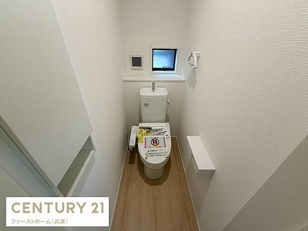 小窓付きで自然光を取り込めるトイレです。温水洗浄便座が装備されています。収納スペースもしっかり確保されています。明るい色調の内装が特徴です。シンプルなデザインで使いやすい空間です。