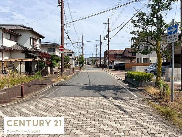 整然と整備された道路が広がり周囲には戸建て住宅が立ち並ぶ住宅街の現地からの眺望です。電柱や配線が遠くまで続き街並みが見渡せる環境です。車通りも落ち着き穏やかな雰囲気が感じられる場所です。