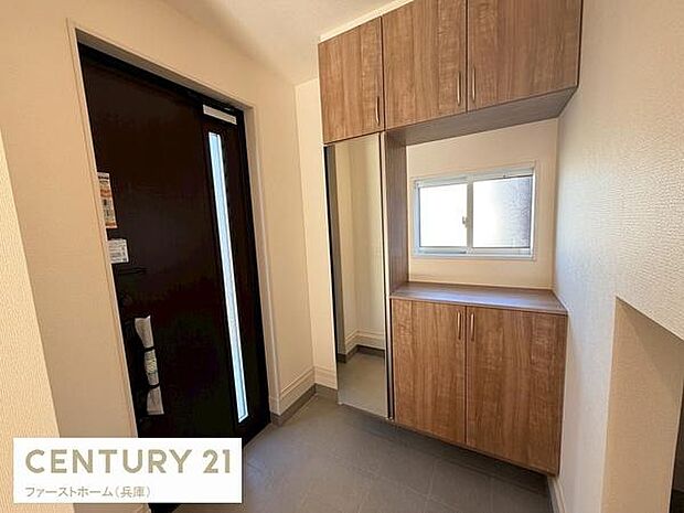 明るい玄関には収納スペースがしっかり設けられております。窓から自然光が入り清潔感のある空間です。落ち着いた色合いの扉と収納が調和しています。すっきりとした印象の玄関で出入りも快適に行えます。