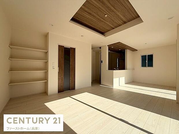 広々としたリビング空間は明るい自然光がしっかりと差し込む設計です。室内のアクセントとなる天井デザインが特徴的です。便利な収納棚も設置されており使い勝手の良さが感じられます。