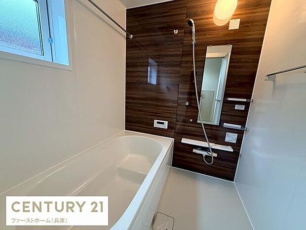 浴室は木目調のアクセントパネルが落ち着いた雰囲気を演出しています。窓が設けられており明るさと換気のしやすさが魅力です。広々としたバスタブでゆったりとした時間を過ごせます。