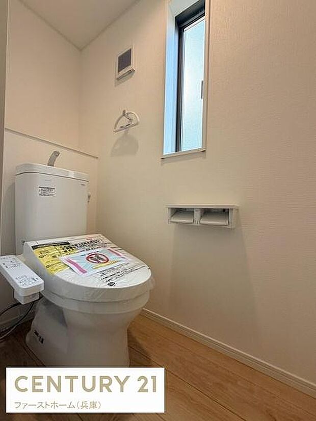 明るい空間に設計されたトイレです。窓付きで換気もしやすく清潔感があります。ナチュラルな床材が特徴です。ペーパーホルダーや収納も設置されています。手洗い機能付きで日常使いに便利です。
