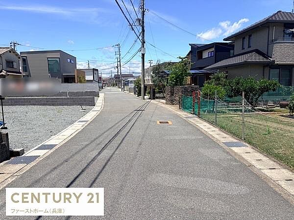 前面道路は舗装されており住環境も整っています。周囲には住宅が並び開放的な雰囲気が広がっています。道路沿いには緑も見られます。周辺の様子が把握しやすい写真です。落ち着いた住宅地の一角です。