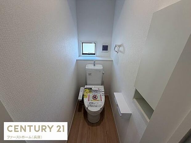 窓が設置されており自然な明るさが感じられるトイレです。設備も新しさを感じさせる仕様となっています。壁面がシンプルで清潔感があります。木目調の床が温かみをプラスしています。