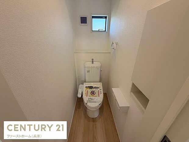 トイレには窓がありしっかりとした換気が可能です。壁面にはペーパーホルダーや収納スペースが設けられ使い勝手の良い空間です。落ち着いた色合いの床材が採用されておりシンプルで清潔感のある印象です。