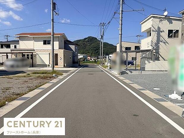現地と前面道路の様子が分かりやすい写真です。周辺には新しい住宅が並んでいます。道路は見通しが良く整備されているのが特徴です。自然に囲まれた住宅地の雰囲気も感じられます。