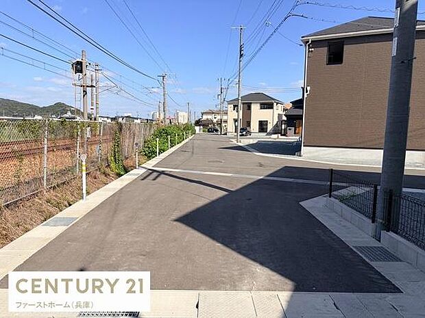 前面道路は舗装されており歩道との区切りも明確です。道路幅にもゆとりがあり車の通行もスムーズに感じられます。周囲には住宅が建ち並び整然とした街並みが広がっています。