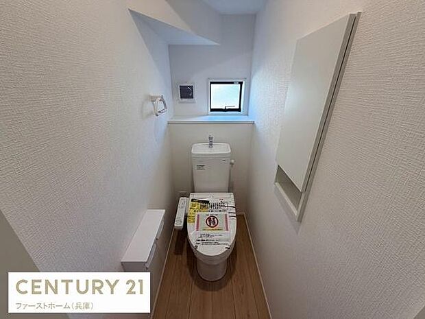 清潔感のあるシンプルなトイレ空間です。小窓から自然光が差し込む造りとなっています。収納スペースも確保され機能性が感じられます。使いやすい配置で整っています。全体的に明るい印象です。