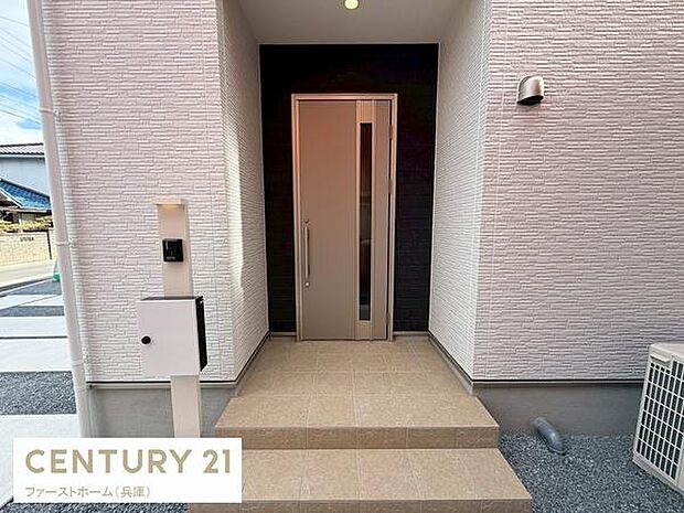 玄関はシンプルで落ち着いた印象です。段差が少なく使いやすい設計になっています。ポストやインターホンも玄関近くに配置されています。建物の外壁も清潔感があります。