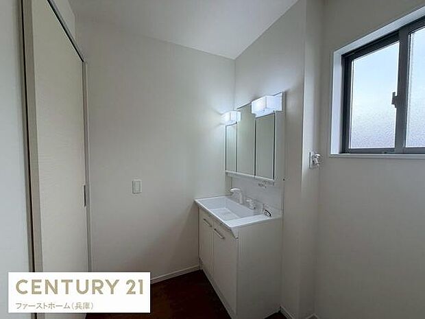 シンプルで清潔感のある洗面台が設置されています。明るい照明が手元をしっかり照らします。大きめの鏡が使い勝手を高めています。収納スペースも備えられており日常使いに便利です。窓からの自然光も取り込めます。