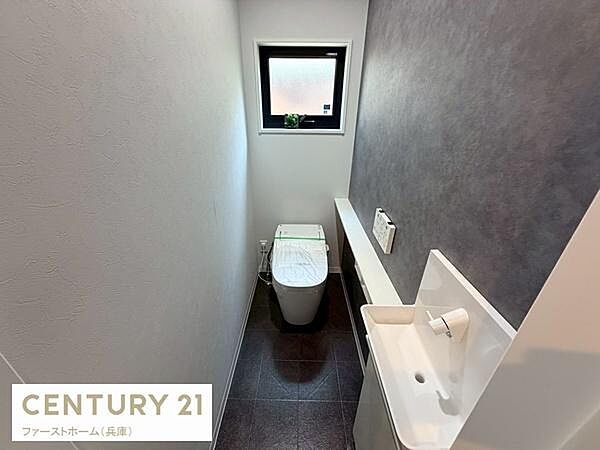 窓からの採光があるトイレで明るい空間が印象的です。壁のアクセントクロスが落ち着いた雰囲気を演出しています。手洗い場が独立して設けられており使い勝手にも配慮されています。