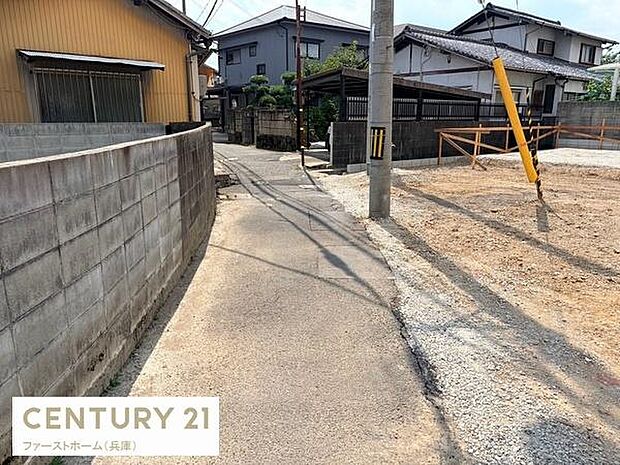 現地写真では周囲が住宅に囲まれており落ち着いた雰囲気の前面道路が確認できます。道路幅や舗装状況もはっきりと映っているため車両の出入りや通行の参考になります。敷地と道路の境界も分かりやすい写真です。