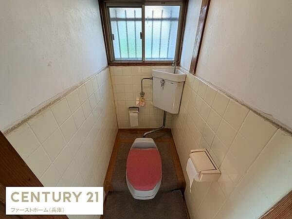 窓付きで明るさを感じられるトイレです。シンプルなレイアウトで使い勝手が良い空間です。壁のタイルが清潔感を演出します。床にはマットが敷かれているため足元でも安心です。換気にも配慮された設計です。