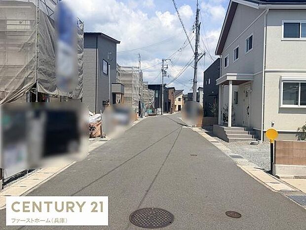幅のある前面道路が特徴でゆとりある街並みが感じられます。周囲には新しい住宅が並び落ち着いた印象です。道路は舗装が整い住環境の整備が進んでいます。電柱や配線が上空に通っている様子が見られます。