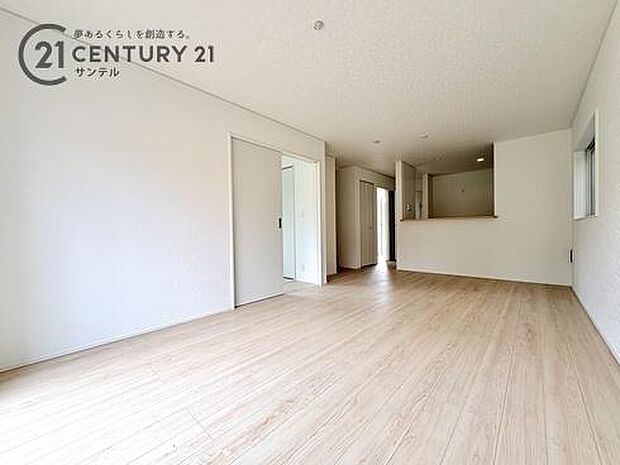 木のぬくもり溢れるフローリングと白壁が調和した、広々とした快適なリビング。家具を配置してもゆとりがあり、対面キッチンから空間全体を見渡せるため、家族の繋がりを常に感じながら心地よくリラックスできます。