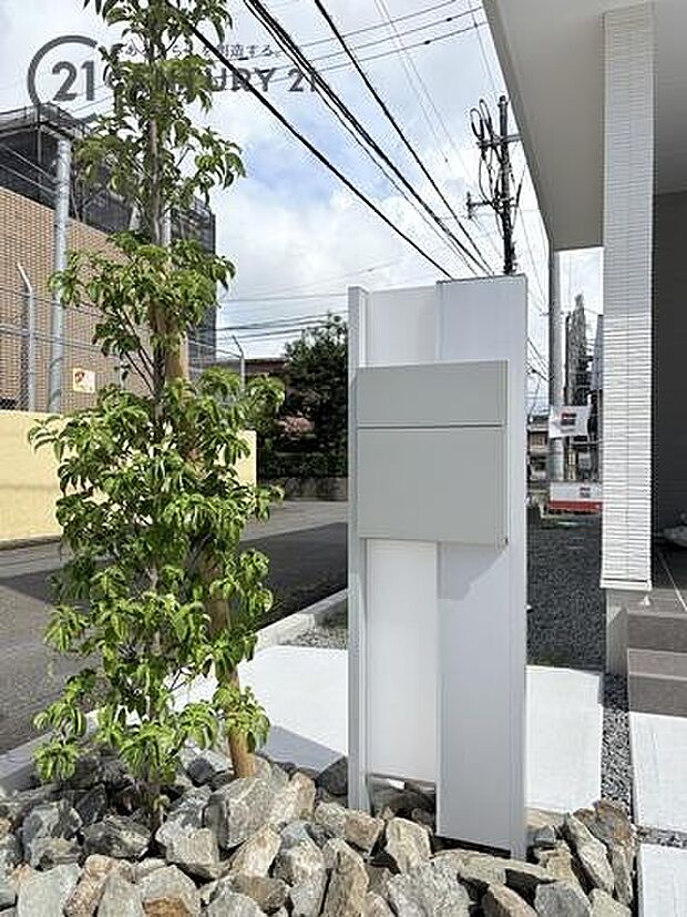 スタイリッシュな機能門柱と緑鮮やかな植栽が迎えるアプローチ
