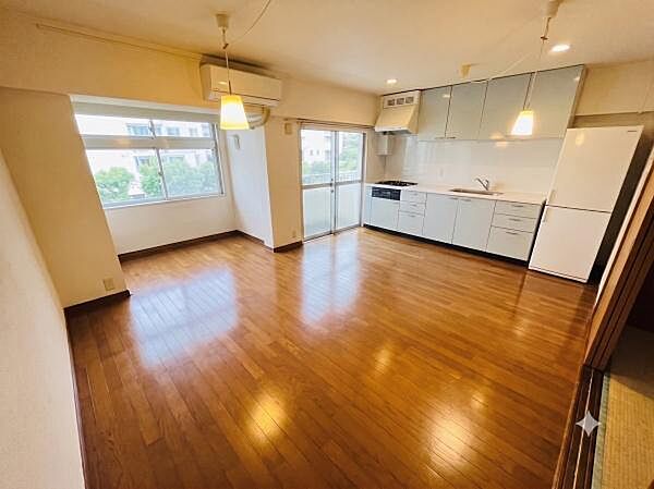 大きな窓からたっぷりの自然光が降り注ぎ、豊かな緑を望む開放的なLDKです。艶のある美しいフローリングと清潔感のあるキッチンが魅力。家具のレイアウトがしやすい広々とした空間で、快適な生活が叶います。