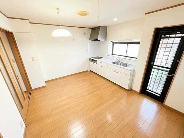 白を基調としたシステムキッチンと明るい木目調フローリングが魅力のダイニングスペースです。勝手口ドアも備わっているため家事動線もスムーズです。※AIによる画像加工を行っております。
