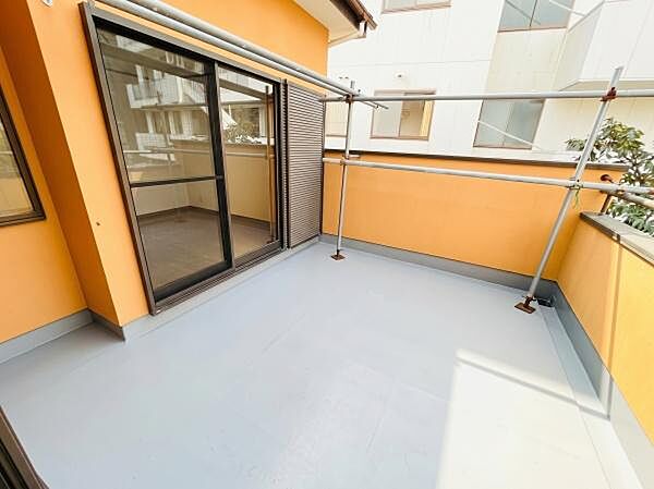 温かみのあるイエローの外壁に包まれた広々としたバルコニーです。日当たり良好で風通しも良く、洗濯物や布団もしっかり干せます。※AIによる画像加工を行っております。