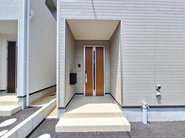 玄関はシンプルなデザインで清潔感のある空間が印象的です。木目調の扉がアクセントとなり落ち着いた雰囲気を演出しています。広めのアプローチが使いやすさを感じさせます。モダンな外観に調和した玄関です。