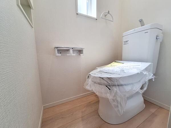 トイレ空間はやわらかな明るさを感じる内装です。小窓が設けられているため換気がしやすい設計です。壁面の一部には小物置きスペースがあり便利です。