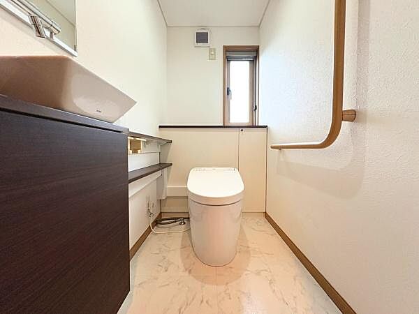 白を基調とした明るい空間が印象的なトイレです。手すりが設置されており使い勝手にも配慮されています。窓があるため自然光を取り入れることができます。収納スペースも備わっています。