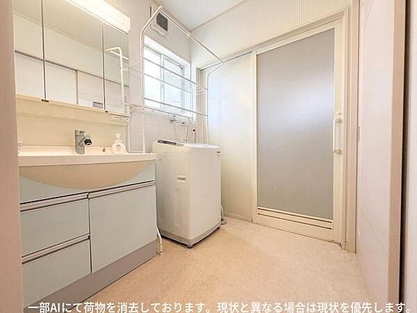洗面台と洗濯機スペースがゆったりと配置されています。大きな鏡と収納が特徴的な洗面所です。室内干しにも活用できるスペースがあります。