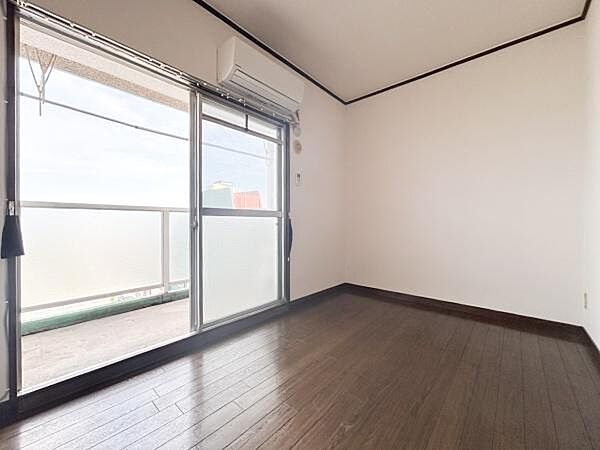 大きな窓から光が差し込む洋室です。壁や床もシンプルで使い勝手の良い空間となっています。エアコン付きで快適に過ごせます。バルコニーへのアクセスも便利な設計です。