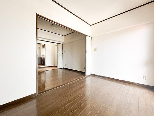 明るい光が差し込む洋室でナチュラルな雰囲気が魅力です。仕切りのドアを開ければ隣室との一体感も楽しめます。白とブラウンのコントラストがシンプルな印象を与えます。床は木目調で落ち着きを感じられます。