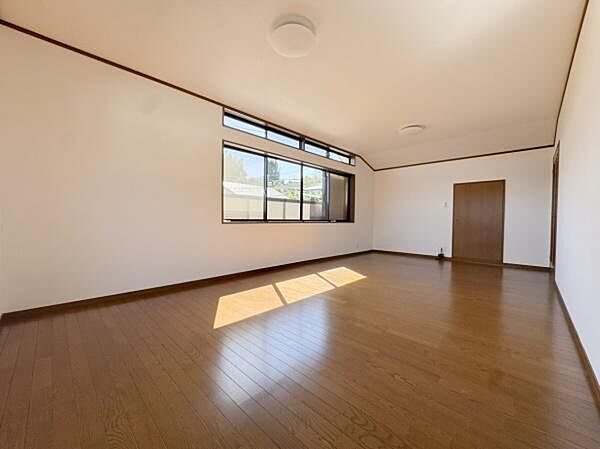 大きな窓からたっぷりと自然光が入る洋室です。木目調の床が空間に温もりを加えています。天井が高めでゆったりとした印象があります。