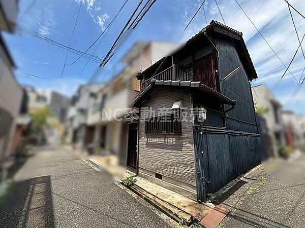 現地土地写真から角地に立地しており両面に道路が接しています。周囲の建物と比べて個性的な外観が特徴です。前面道路の幅員がしっかり確保されておりアクセスも良好です。