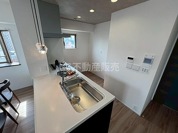 窓からの光が差し込む明るいキッチンです。カウンター付きで開放感があります。シンプルなデザインで空間がすっきりとしています。コンパクトながら機能的な仕様が魅力です。モダンな雰囲気を感じる内装です。