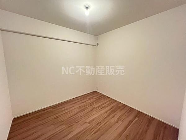 洋室はシンプルな内装で落ち着いた雰囲気が感じられます。天井の照明が柔らかく空間を照らします。フローリングの質感が室内全体に温かみを与えています。壁が白く清潔感のある仕上がりとなっています。