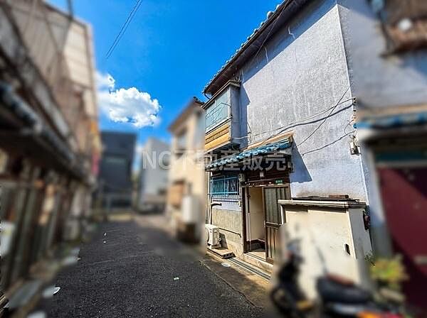 晴れた空の下前面道路に面した現地写真です。道路幅があり建物外観がしっかり確認できます。周辺の雰囲気も分かりやすい一枚です。日当たりの状況やアクセスのしやすさが伝わります。