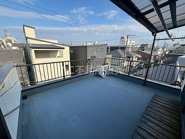 開放感のあるバルコニーは広々としたスペースが特長です。屋根付きで急な天候変化にも対応しやすい設計です。周辺の住宅街を見渡せる眺望が楽しめます。物干し用の設備も備えています。