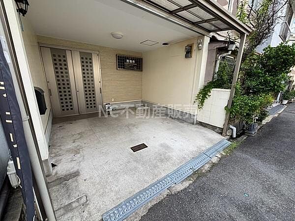 屋根付きの駐車スペースで天候に左右されず車を保管できます。出し入れしやすい形状で車庫の奥には扉が設置されています。周囲がすっきりと整備されており清潔感のある印象です。