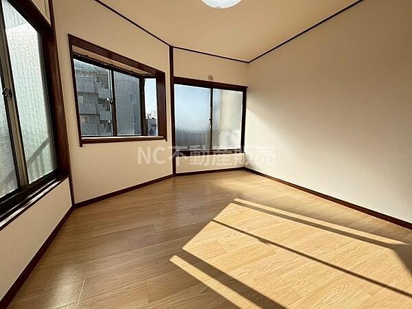リビングは大きな窓から自然光がたっぷり入る明るい空間です。角部屋ならではの開放感が魅力です。木目調のフローリングで温かみがあります。落ち着いた色合いの内装が印象的です。天井照明も設置済みです。