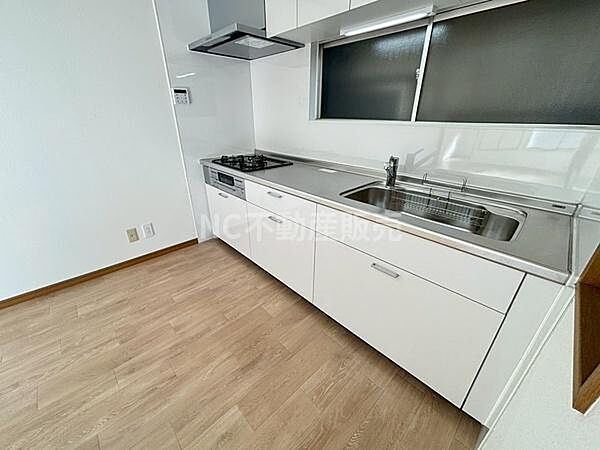 キッチンはシンプルで清潔感のあるデザインです。広々とした作業スペースが確保されています。窓があり光が差し込みやすい環境です。収納も多く使いやすいレイアウトになっています。