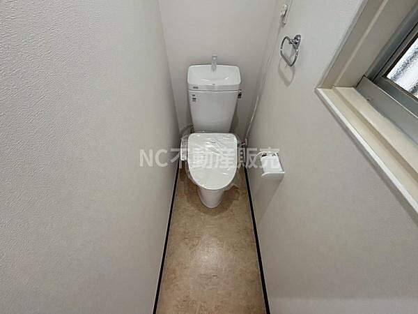 窓付きで換気がしやすいトイレです。壁面にはペーパーホルダーやタオルリングが設置されています。シンプルで手入れのしやすい空間です。床材は掃除しやすい素材となっています。