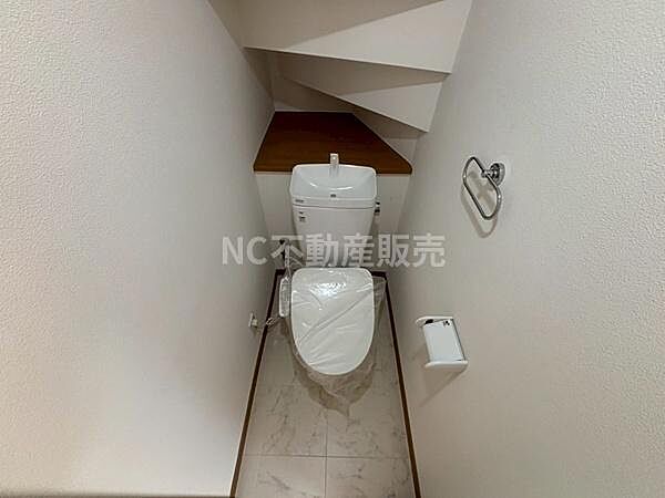 コンパクトにまとめられたトイレ空間です。階段下のスペースを有効利用しています。清潔感のある床材が採用されています。ペーパーホルダーやタオルリングなど基本設備が揃っています。
