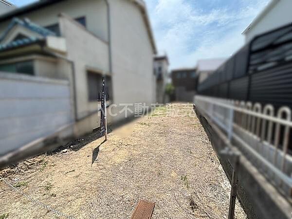 現地土地写真から敷地全体の様子が確認できます。周囲には住宅が建ち並び落ち着いた雰囲気です。道路に面しているため車両の出入りもしやすい印象があります。日当たりも確保しやすい環境です。