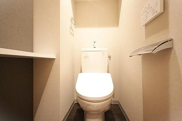 清潔感のあるトイレ空間です。壁に設置された操作パネルで快適にご利用いただけます。ペーパーホルダーもスタイリッシュです。収納棚も設けられており便利にお使いいただけます。