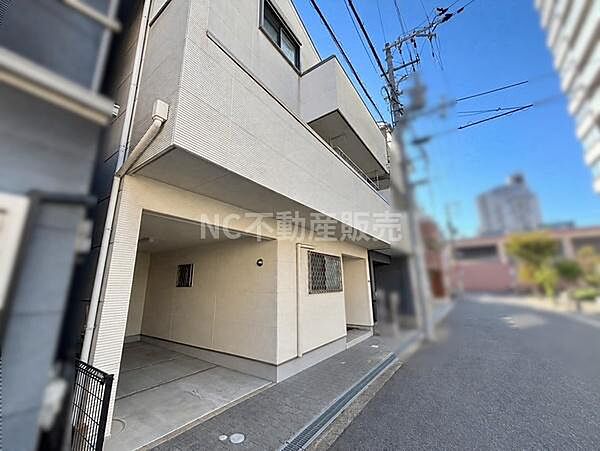 前面道路が幅広く車の出し入れもしやすい立地です。建物の外観はシンプルで清潔感があります。周囲に高い建物がありながらも開放的な印象を受けます。車庫スペースも屋根付きで安心です。