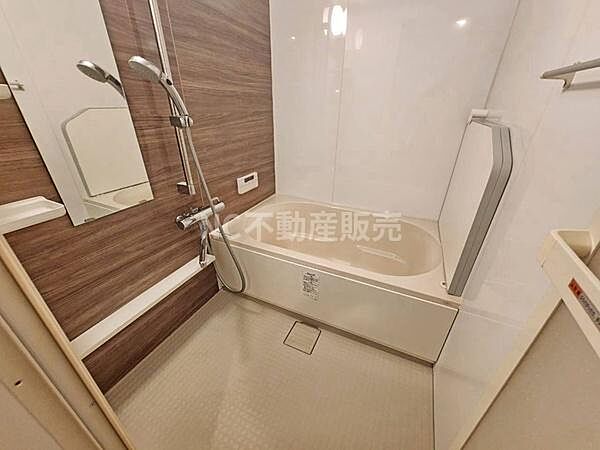 浴槽とシャワーが備わったバスルームです。木目調のパネルがアクセントとなっており明るい印象です。壁面にはミラーも設置されていて使いやすい空間です。洗い場もゆったりとしています。お掃除もしやすい設計です。