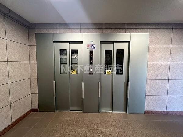 シンプルで洗練されたデザインのエレベーターホールです。壁や床の仕上げが落ち着いた雰囲気を演出しています。照明も明るく清潔感が感じられます。各階への移動がスムーズに行える設計です。
