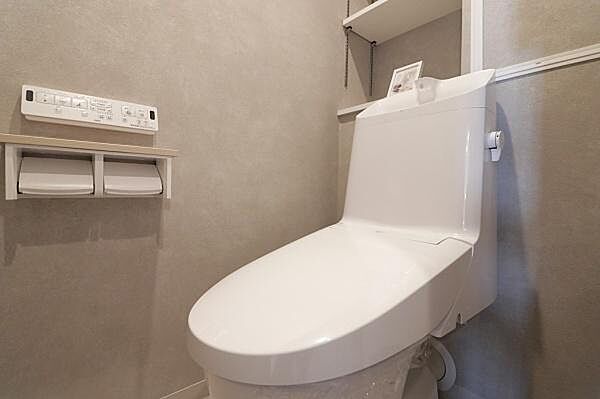 清潔感のあるトイレで壁の色合いが落ち着いた雰囲気を演出しています。収納スペースも設けられており使い勝手に配慮されています。機能的なパネル操作も可能な仕様です。