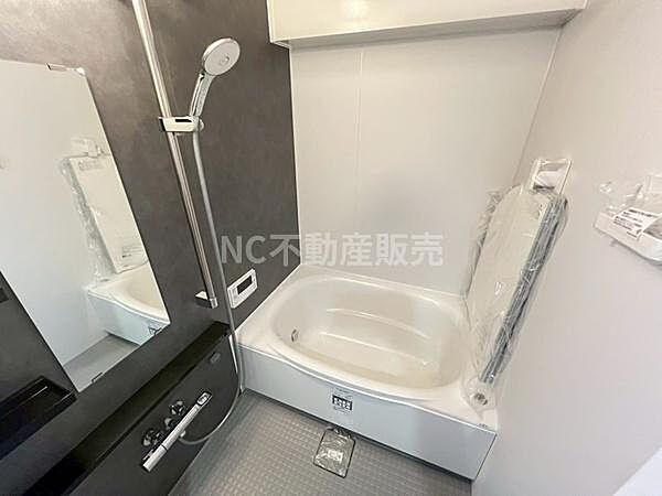 浴室全体がシンプルなデザインでまとめられており清潔感があります。ダークカラーの壁面と大きな鏡が特徴的です。浴槽とシャワーがひとつの空間に配置されており使い勝手が良いです。