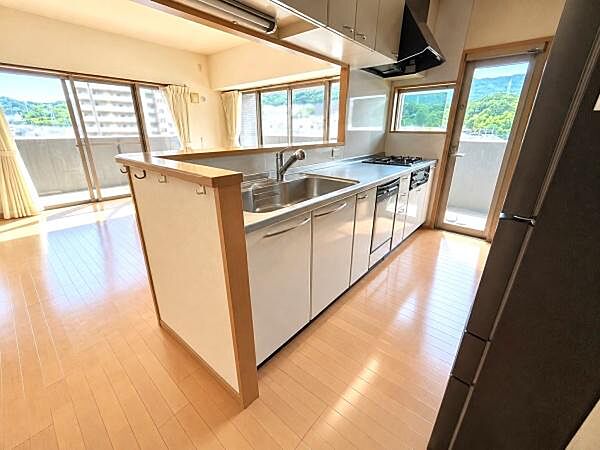 リビングを見渡せる開放的な対面式カウンターキッチンです。窓からは自然光が差し込み、眺望も良好。収納キャビネットも充実しており、調理器具や食器類をすっきり整理できます。上部吊り戸棚も完備。