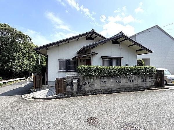 道路から建物全体を見渡せるアングル。2方向に接道しており、開放感があります。背後に広がる豊かな緑も魅力のひとつです。
